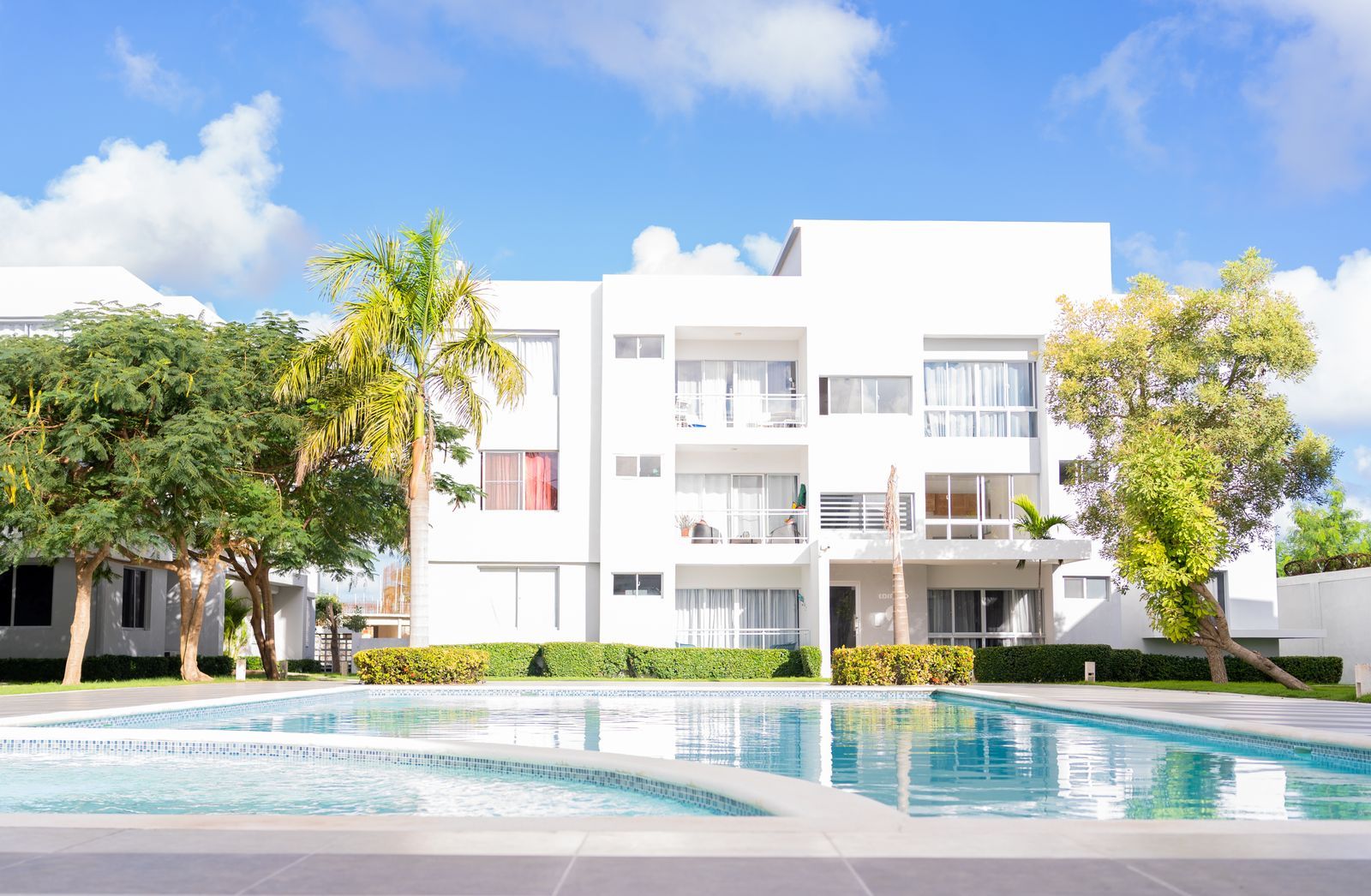 White apartment building with an outdoor pool and deck (stock photo)