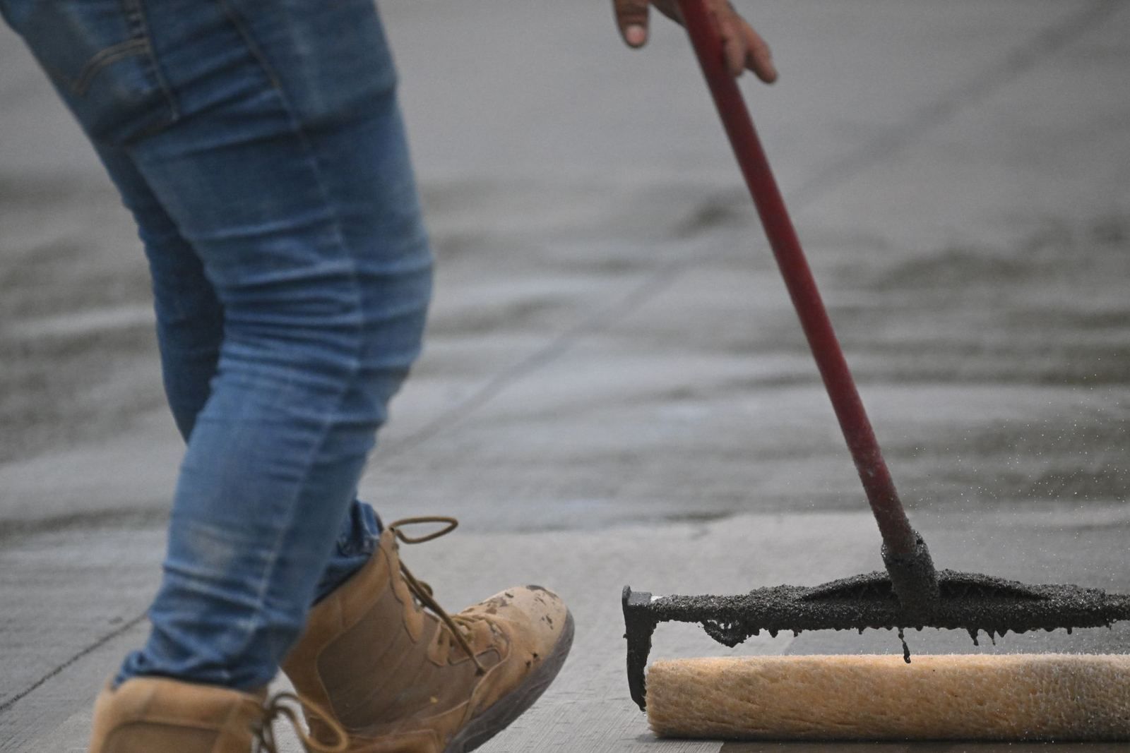 Worker rolling sealer onto concrete (stock photo)