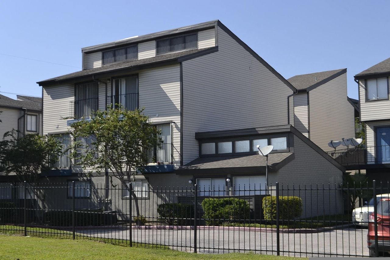 Low-rise townhome-style apartments behind a fence with a paved drive in Houston, Texas (stock photo)